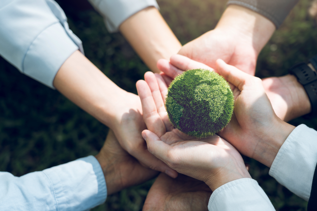 Handen die een kleine groene wereldbol vasthouden