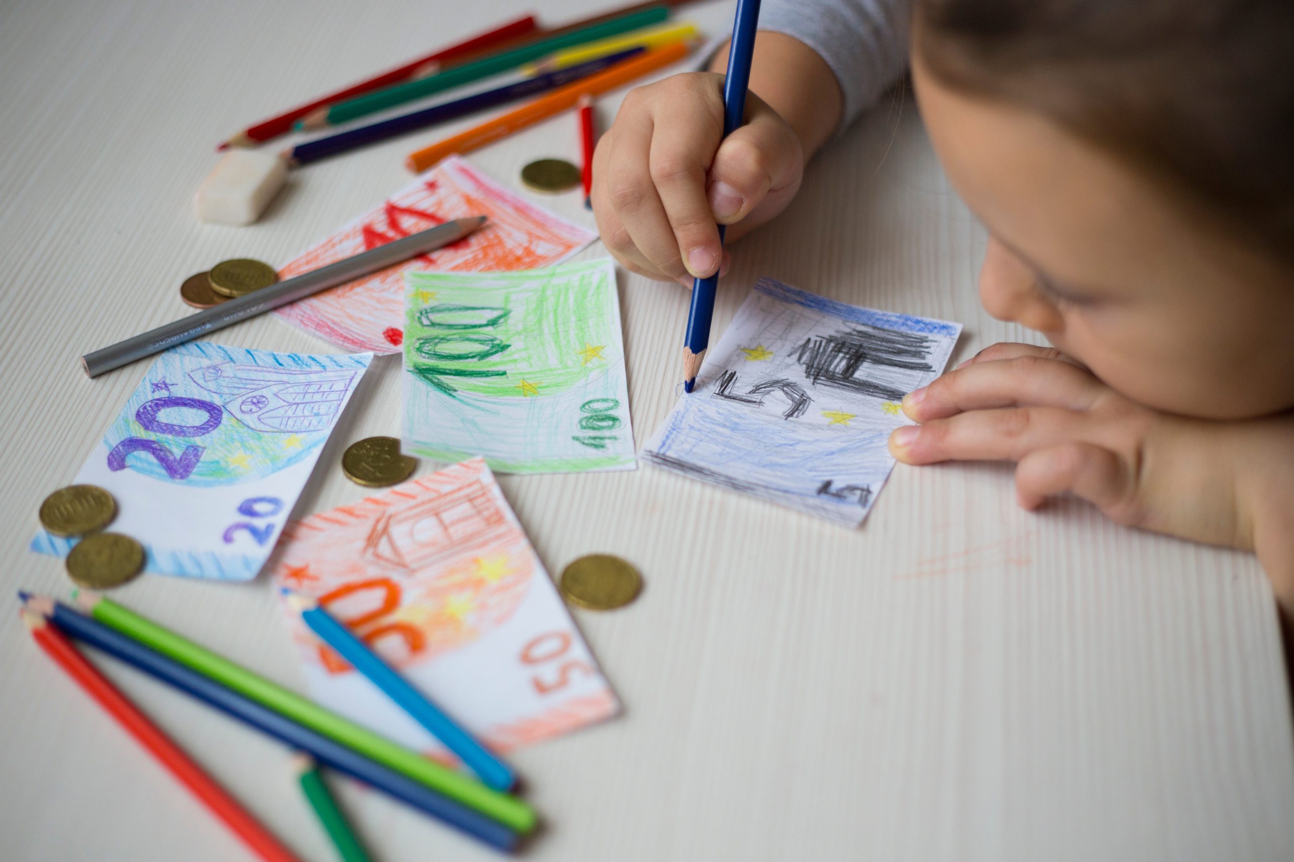 Meisje kleurt bankbiljetten met potloden