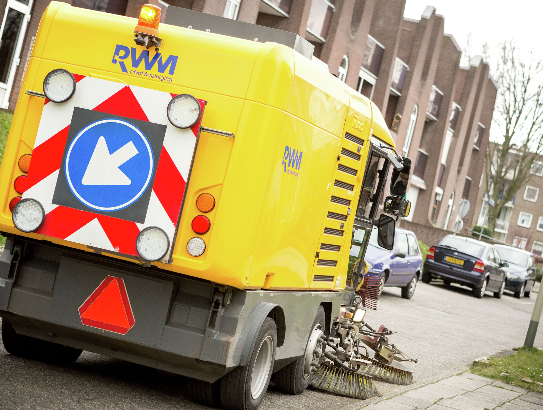 Een veegwagen die de straat schoonmaakt in een straat in Sittard-Geleen.